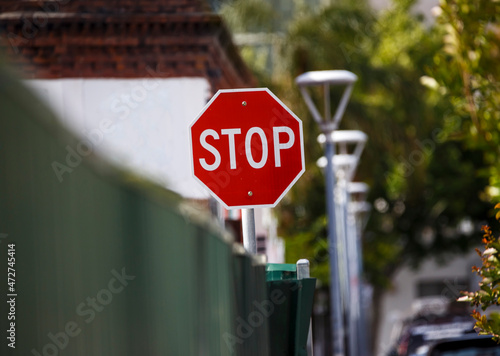 Stop sign behind a green fence in a city in Adelaide, South Australia