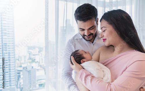 Portrait of Asian parents with newborn baby, Closeup portrait of asian young couple father mother holding new born baby in apartment. Happy asia lovely family, nursery breastfeeding mother’s day photo