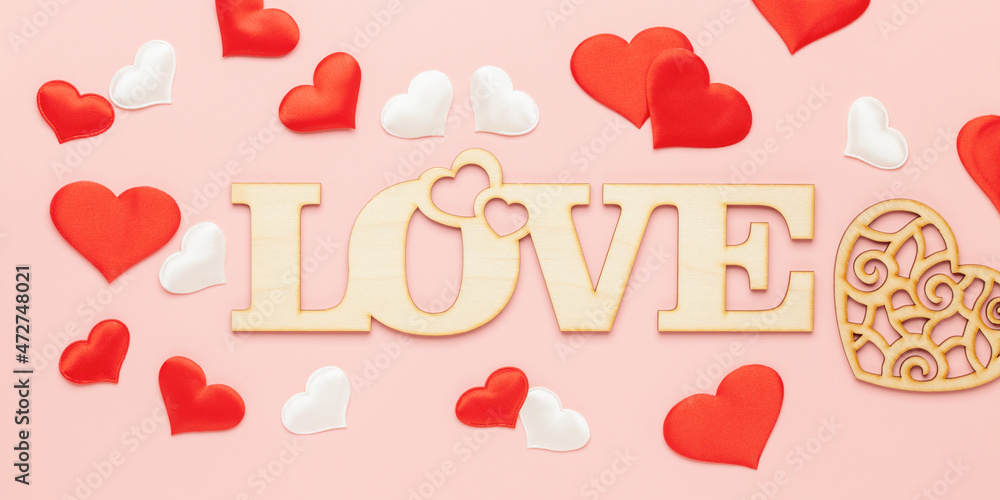 The word love in wooden letters and textile hearts on pink background. Happy Valentine's Day,World Women's Day  concept. Top view