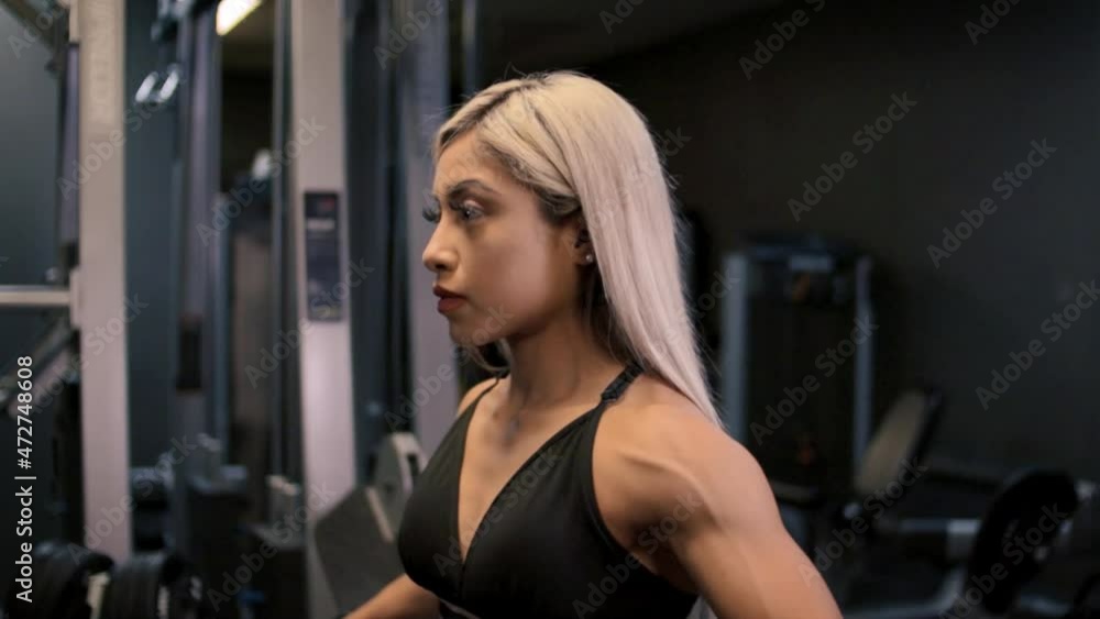 Female using dumbbells to perform arm raises, mid shot side profile Female using dumbbells to perform arm raises, mid shot side profile