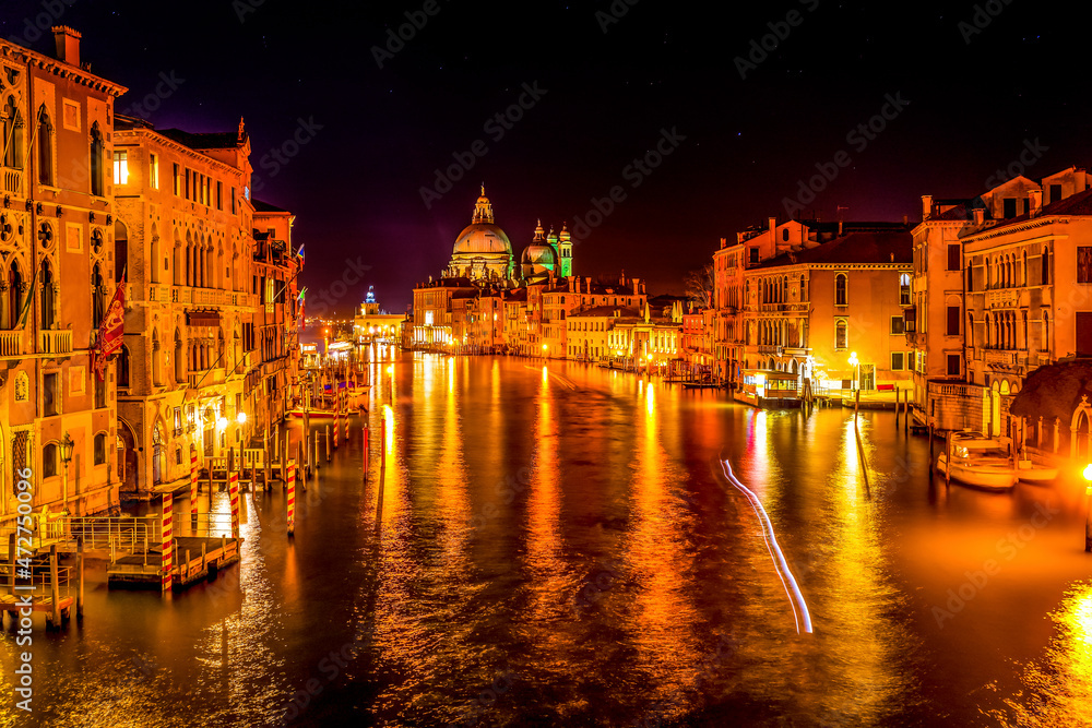 Colorful Grand Canal and Santa Maria della Salute church at night with reflection in Venice, Italy.