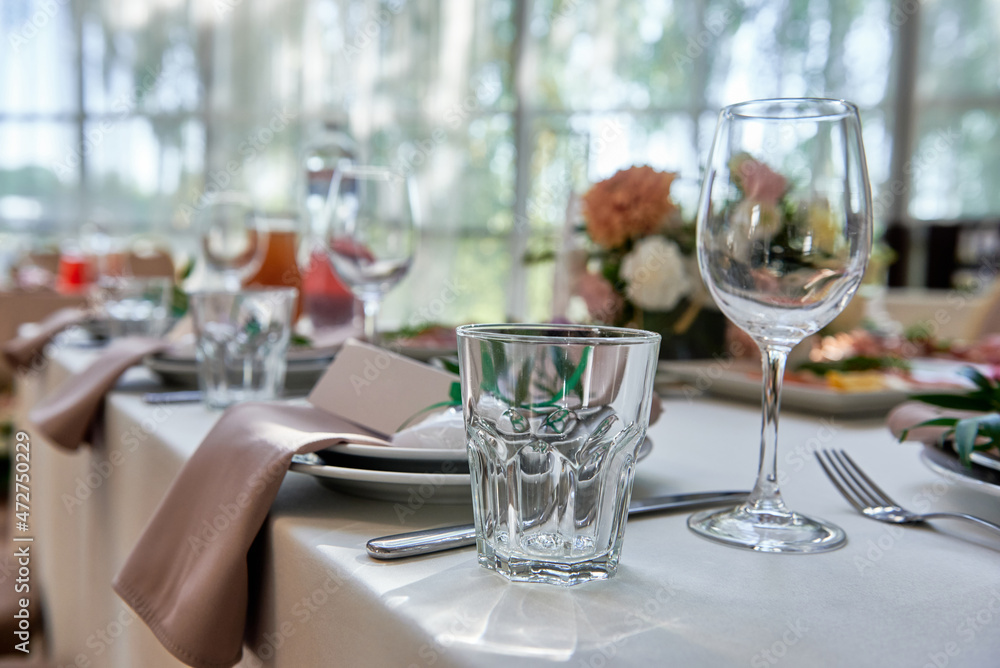 Table setting with sparkling wineglasses, plate with beige napkin and cutlery on table, copy space. Place set at wedding reception. Table served for wedding banquet in restaurant Table setting with sparkling wineglasses, plate with beige napkin and cutlery on table, copy space. Place set at wedding reception. Table served for wedding banquet in restaurant