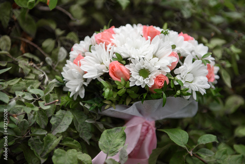 Close up of bridal bouquet of pink and white flowers with satin ribbon on green grass background, copy space. Wedding concept.