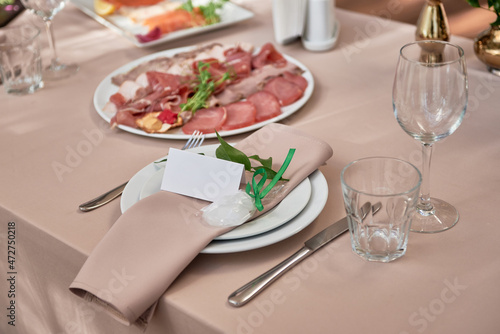 Table setting with sparkling wineglasses  plate with beige napkin and cutlery on table  copy space. Place set at wedding reception. Table served for wedding banquet in restaurant