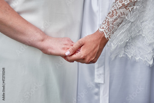 Mother and daughter holding hands on wedding day indoors, copy space