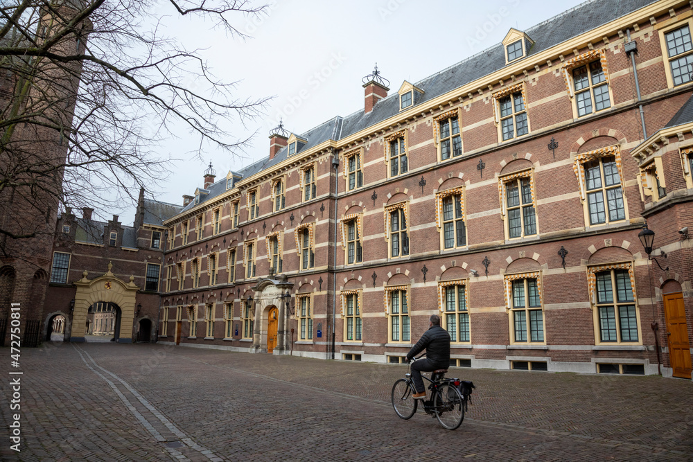 Obraz premium Europe, Netherlands, The Hague. Cyclist rides toward entrance to Binnenhof.