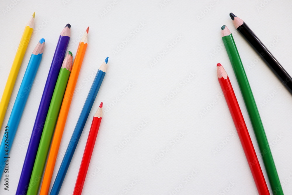 Colored pencils isolated on table, on paper, on white background. Flat lay, top view. Colored pencils isolated on table, on paper, on white background. Flat lay, top view.