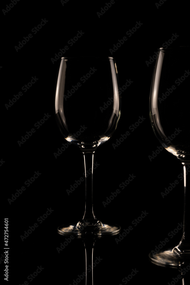 Set of empty crystal wine glasses, with black background and transparent tones.