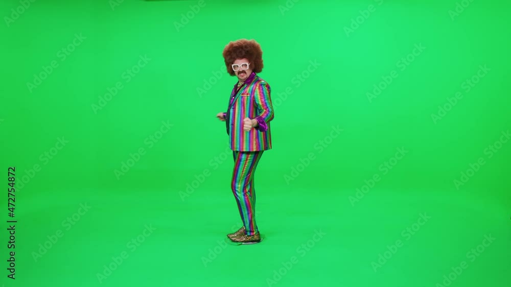 Retro dude in a funny wig and multicolored suit is dancing a funny spinning dance on a green background, a festive mood, a retro disco man is having fun at a new year's party. Retro dude in a funny wig and multicolored suit is dancing a funny spinning dance on a green background, a festive mood, a retro disco man is having fun at a new year's party.