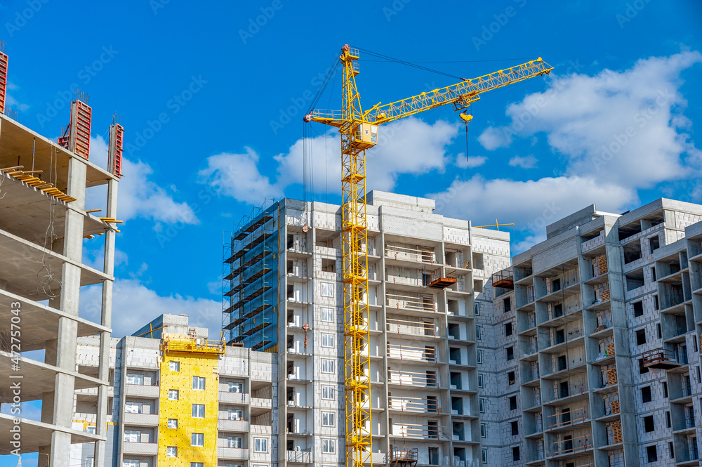 Construction site background. Crane and construction of a new multi-storey residential complex of buildings.