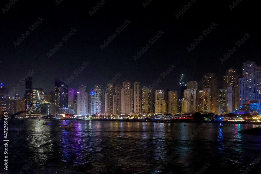 Fototapeta premium Panoramic view at night of Business Bay district with reflection in sea, UAE. Aerial sky at highest buildings in central Dubai, United Arab Emirates. High quality photo