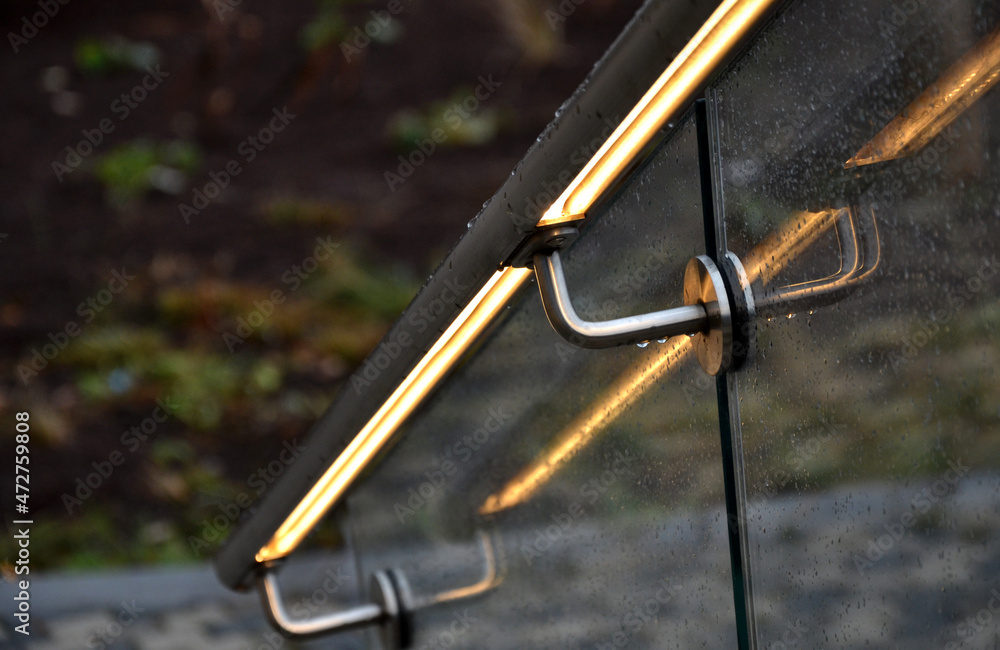 from the bottom of the handle is a recessed LED strip with a yellow light. the side of the stair railing is made of glued glass panels without frames. stainless steel railing bars on metal handles