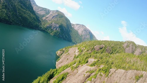 Shooting from helicopter amazing nature valley with high mountains and wide river top view. Aerial shot beautiful environment landscape at summer sunny day surrounded by glare sky. photo