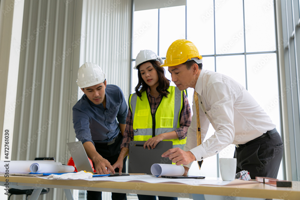 Team of Engineers architects working and standing around table working on blueprint at construction plans. Engineers discussing. Team of Engineers architects working and standing around table working on blueprint at construction plans. Engineers discussing.