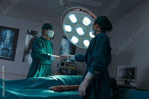 Confidence team of professional surgeons handshaked emergency patient treatment in hospital operating room.