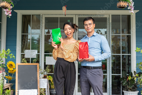 Cheerful business owners standing welcomingly together in front of the counter of their cafe.