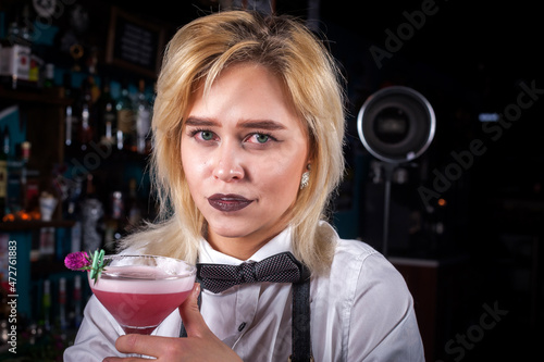 Girl barman concocts a cocktail behind the bar photo