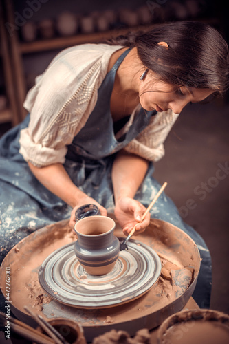 Charming young and cheerful woman demonstrates the process of making ceramic dishes using the old technology. Handmade products.