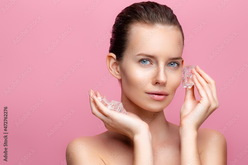 beautiful brunette caucasian female with perfect skin holds ice cube near face on pink background beautiful brunette caucasian female with perfect skin holds ice cube near face on pink background