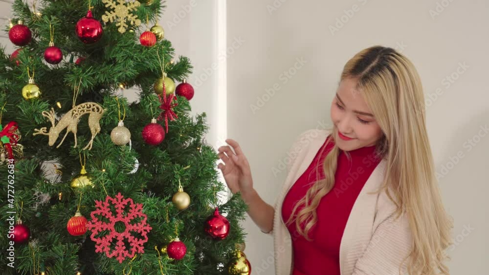 women arrange ornament on tree for Christmas day, lifestyle of couple romance lover happy merry christmas holiday with tree before new year at home women arrange ornament on tree for Christmas day, lifestyle of couple romance lover happy merry christmas holiday with tree before new year at home