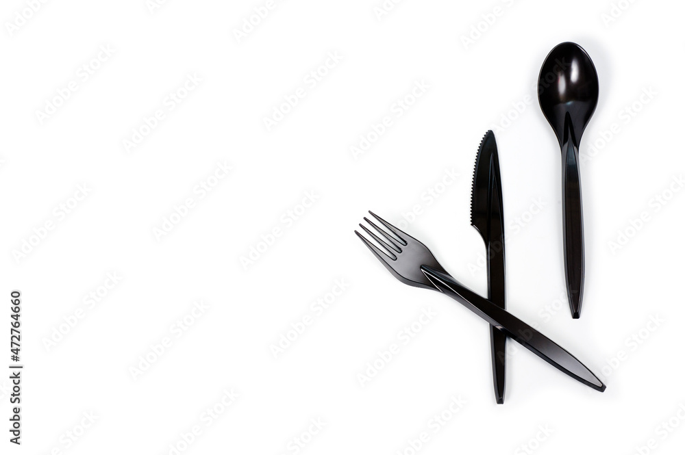 Fototapeta premium A set of plastic cutlery knife, fork and spoon in black, filmed on a white background