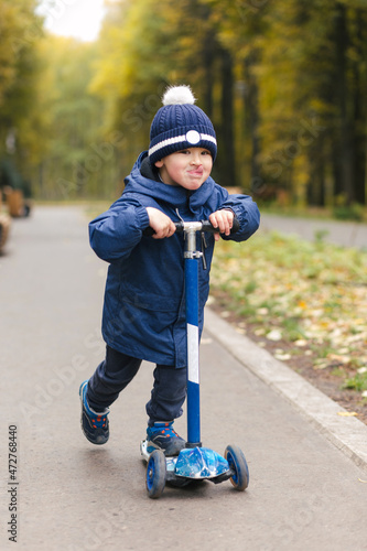 Adorable funny toddler riding on a scooter in scate park in stylish outfit