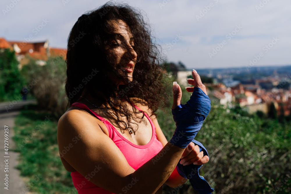 Obraz premium Photo of a strong fitness woman boxer in gloves posing outdoors.
