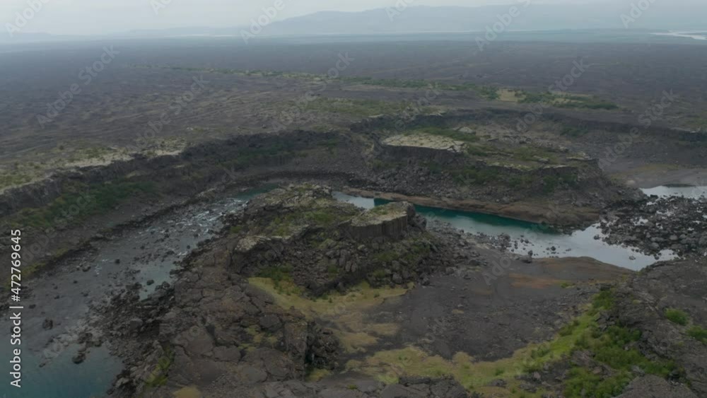 Birds eye surreal panorama of black rock basalt cliffs in Iceland. Drone view of Aldeyjarfoss waterfall highlands with river flowing and volcanic formations Birds eye surreal panorama of black rock basalt cliffs in Iceland. Drone view of Aldeyjarfoss waterfall highlands with river flowing and volcanic formations