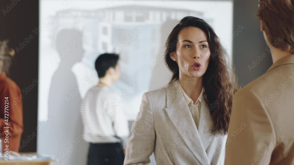 Beautiful biracial woman smiling and speaking with male colleague on business event Beautiful biracial woman smiling and speaking with male colleague on business event