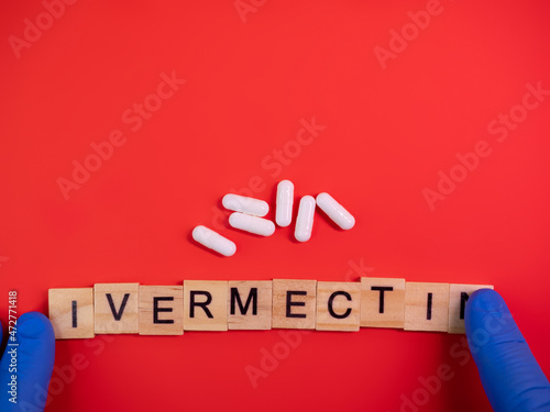 Ivermectin on colored red paper texture background. Ivermectin antiparasitic medication. Off label approved medicine drugs use. Covid-19 therapy. Pharmacy concept. Copy space. Mock up design template photo