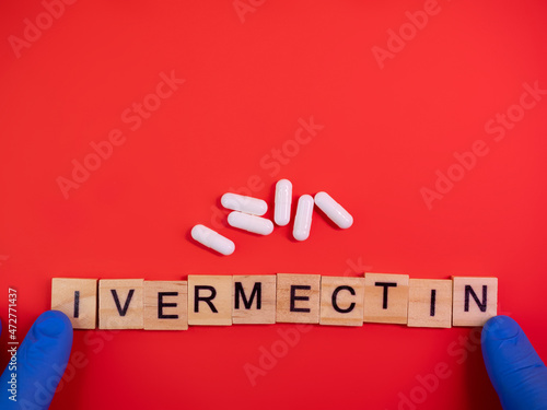 Ivermectin on colored red paper texture background. Ivermectin antiparasitic medication. Off label approved medicine drugs use. Covid-19 therapy. Pharmacy concept. Copy space. Mock up design template photo