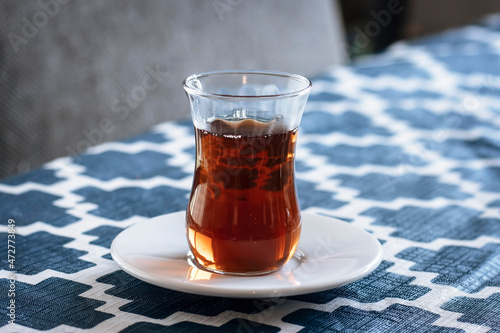 Turkish tea in a traditional glass on a white saucer.  The Tulip shaped glass is called ince belli meaning slim-waisted.  photo