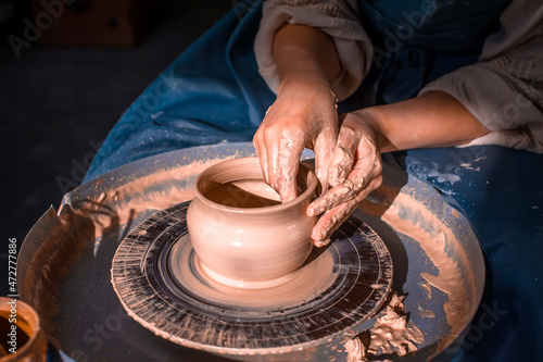 Young lady enjoying pottery art and production process. Artisan production. Close-up. photo