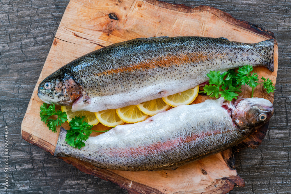 Two fresh raw rainbow trouts garnished with lemon slices and parsely Two fresh raw rainbow trouts garnished with lemon slices and parsely