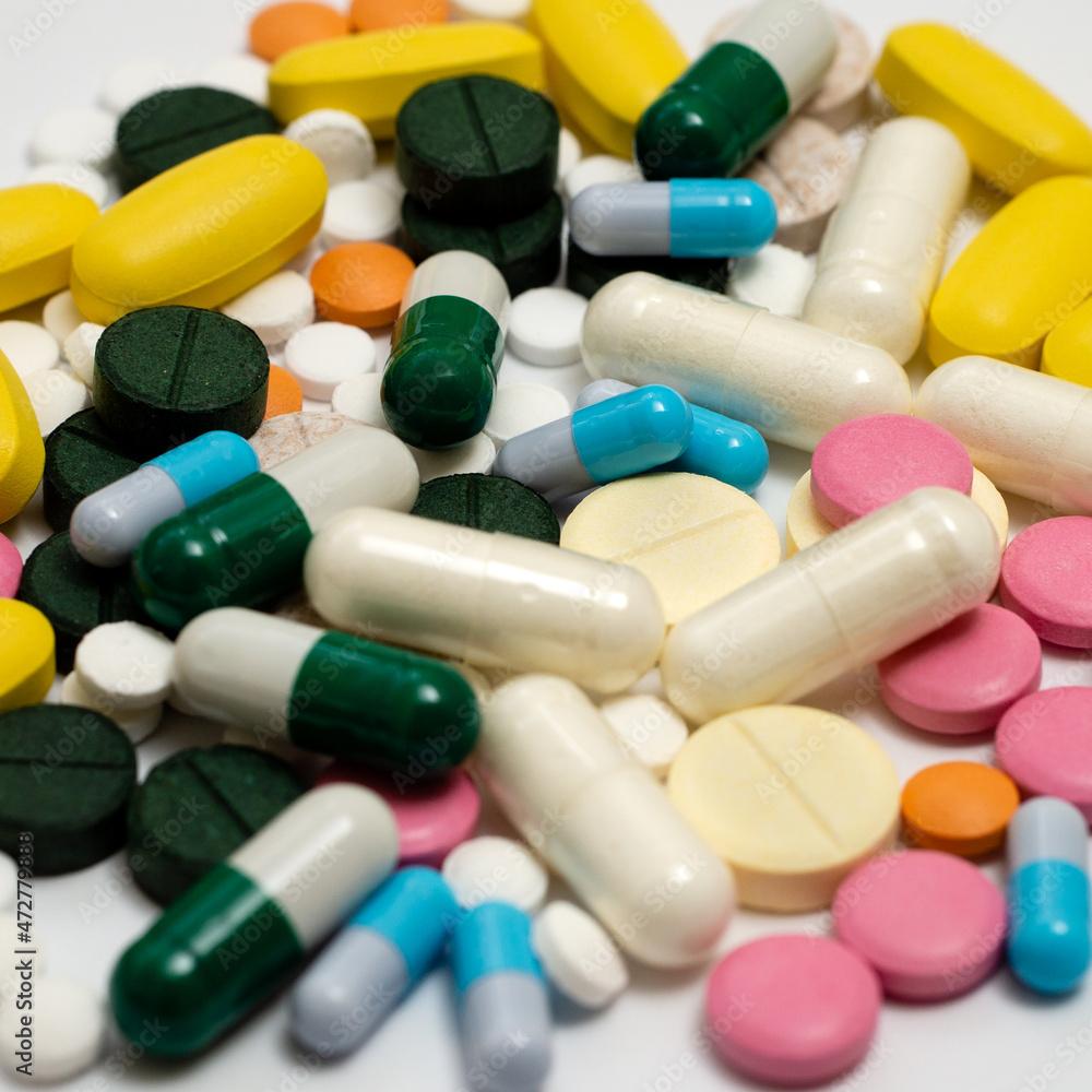 Variety of medicines and capsules in a woman's palm on a blue background. The concept of consuming a large number of drugs Variety of medicines and capsules in a woman's palm on a blue background. The concept of consuming a large number of drugs