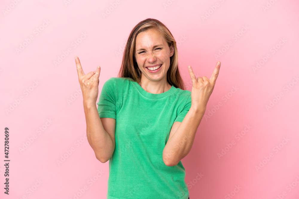Young English woman isolated on pink background making horn gesture Young English woman isolated on pink background making horn gesture