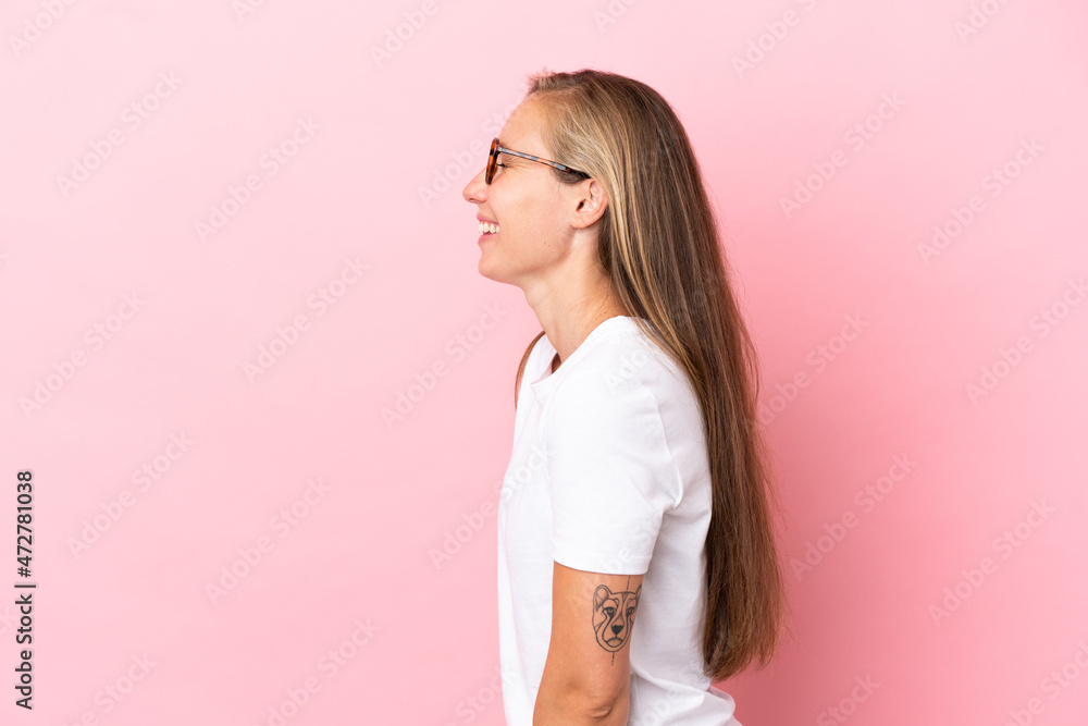 Young English woman isolated on pink background laughing in lateral position Young English woman isolated on pink background laughing in lateral position