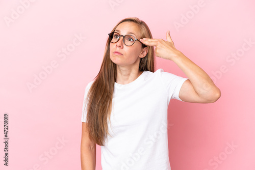 Young English woman isolated on pink background with problems making suicide gesture