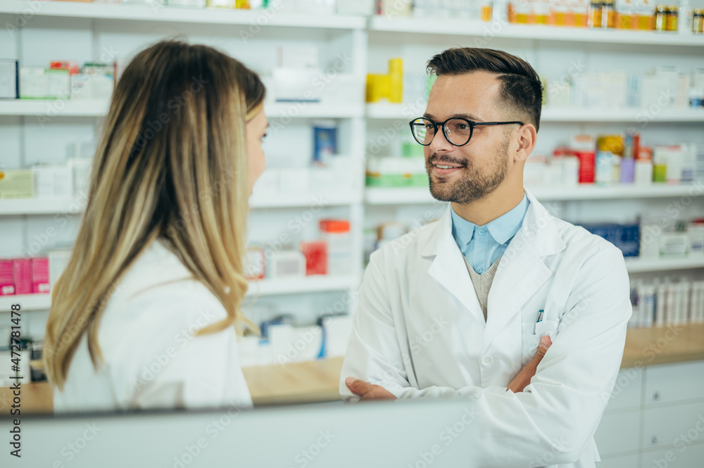 Happy young male and female colleagues pharmacist working in a pharmacy