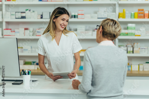 Male pharmacist selling medications at drugstore to a senior woman customer photo