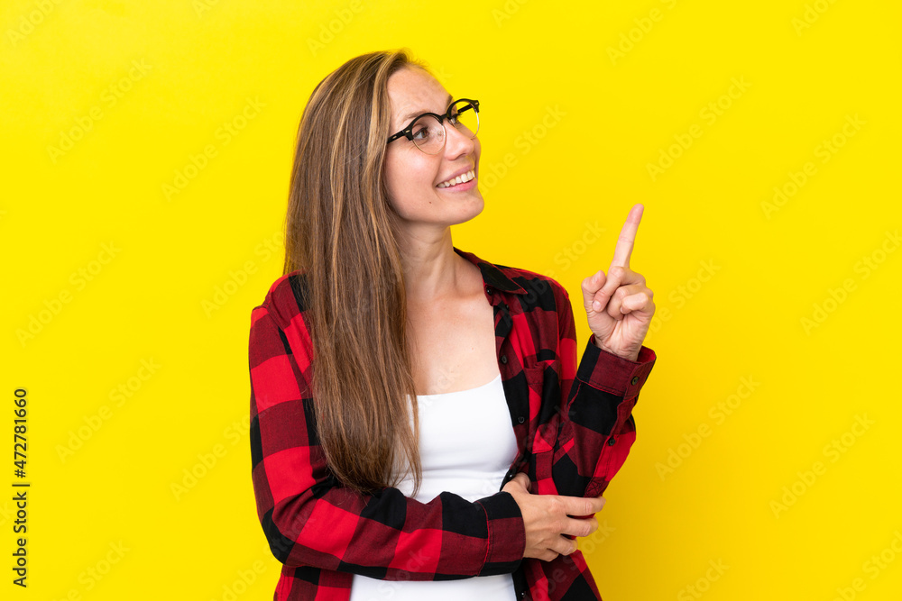 Young English woman isolated on yellow background pointing up a great idea Young English woman isolated on yellow background pointing up a great idea