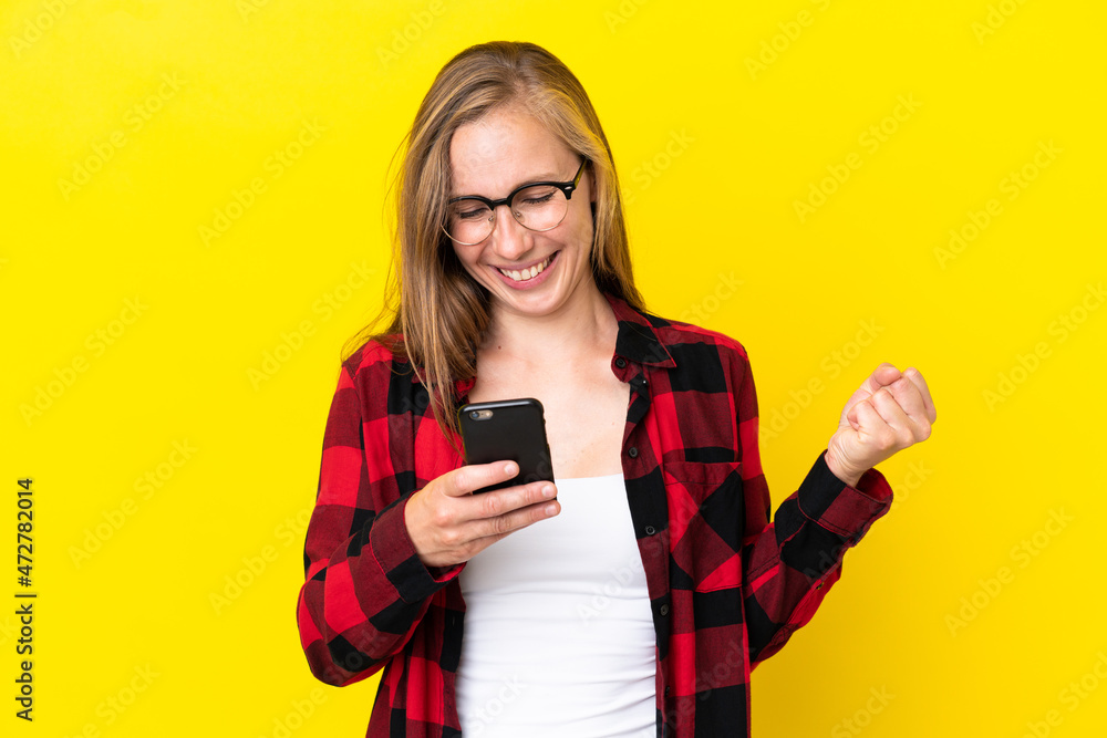 Young English woman isolated on yellow background surprised and sending a message Young English woman isolated on yellow background surprised and sending a message