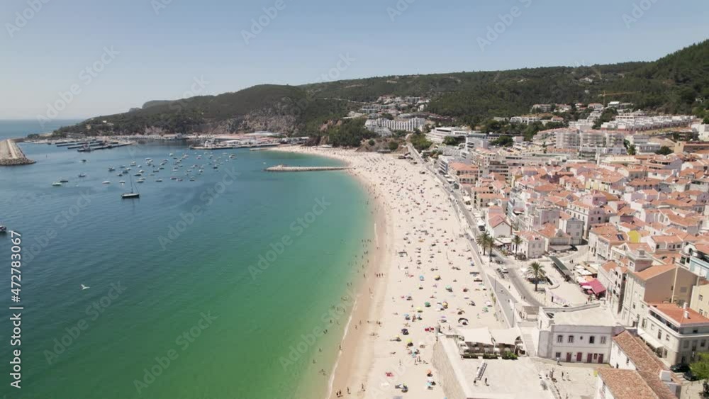 Aerial backwards view of long and beautiful beach with its bay in Sesimbra. Portugal. Real time Aerial backwards view of long and beautiful beach with its bay in Sesimbra. Portugal. Real time