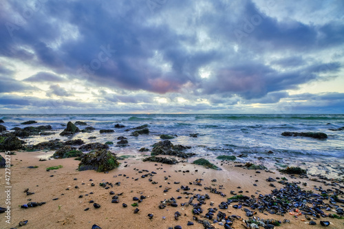 Fototapeta Naklejka Na Ścianę i Meble -  Landscape, seascape sunset on the coast of Huisduinen, the Netherlands. long exposer of waves, dramatic sky, detailed, seaweed, rocks
