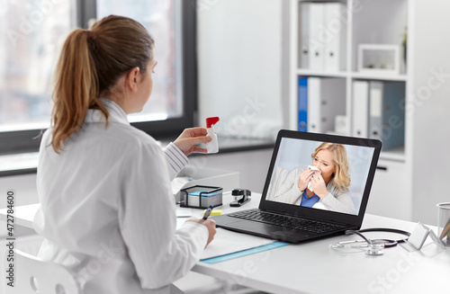healthcare, technology and medicine concept - female doctor with laptop computer having video call with middle aged patient and showing oral spray at hospital