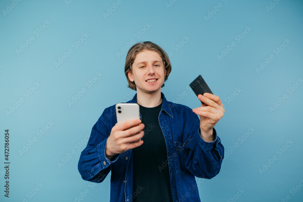 Portrait of a surprised guy in a wild shirt on a blue background, looking at the camera with a shocked face and spreads his arms. Portrait of a surprised guy in a wild shirt on a blue background, looking at the camera with a shocked face and spreads his arms.