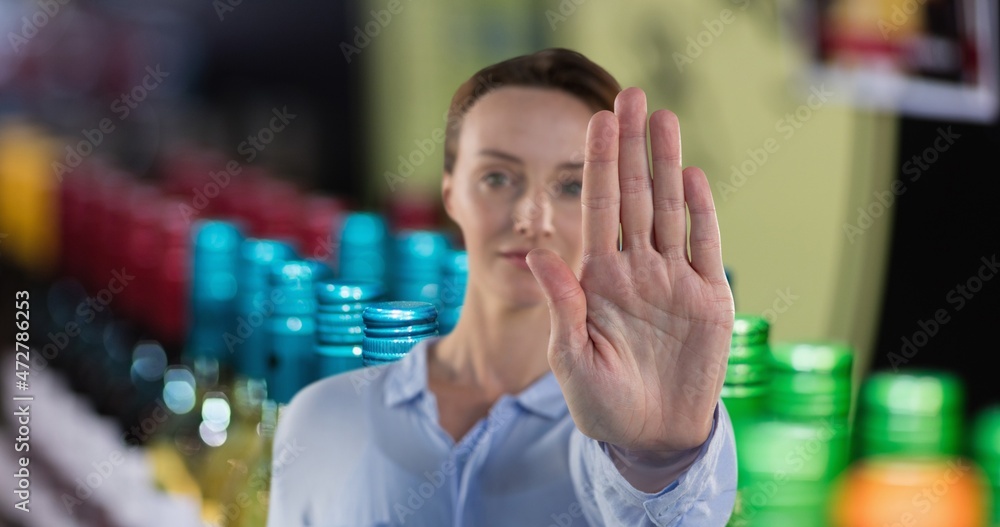 Portrait of woman showing stop gesture with hand at wine shop