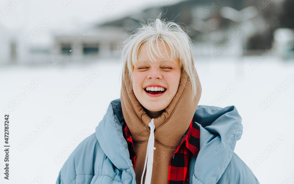 Φωτογραφία Close portrait of happy teen girl with blond hair on a snowy snowy background in winter, smiling with closed eyes