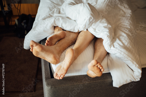 The feet of a young heterosexual couple relaxing in bed.