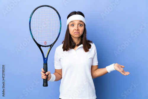 Young woman tennis player over isolated background having doubts while raising hands
